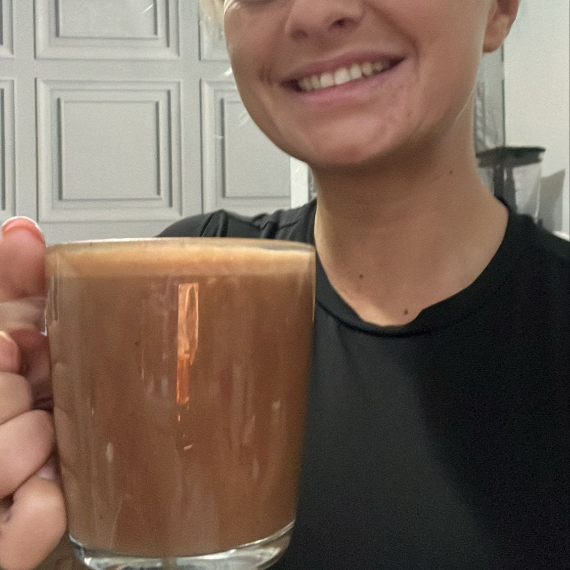 "Person holding a glass of hot chocolate in a home setting"