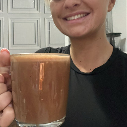 "Person holding a glass of hot chocolate in a home setting"